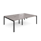 Large modular bench desk with a grey wood-effect top, integrated cable access slots, and black metal legs, shown on a white background.