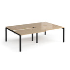 Large modular bench desk with a light wood-effect top, integrated cable access cut-outs, and black metal legs, shown on a white background.