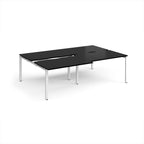 Large modular bench desk with a black worktop, integrated cable access cut-outs, and white metal legs, shown on a white background.