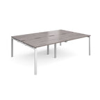 Large modular bench desk with a grey wood-effect top, integrated cable access slots, and white metal legs, shown on a white background.