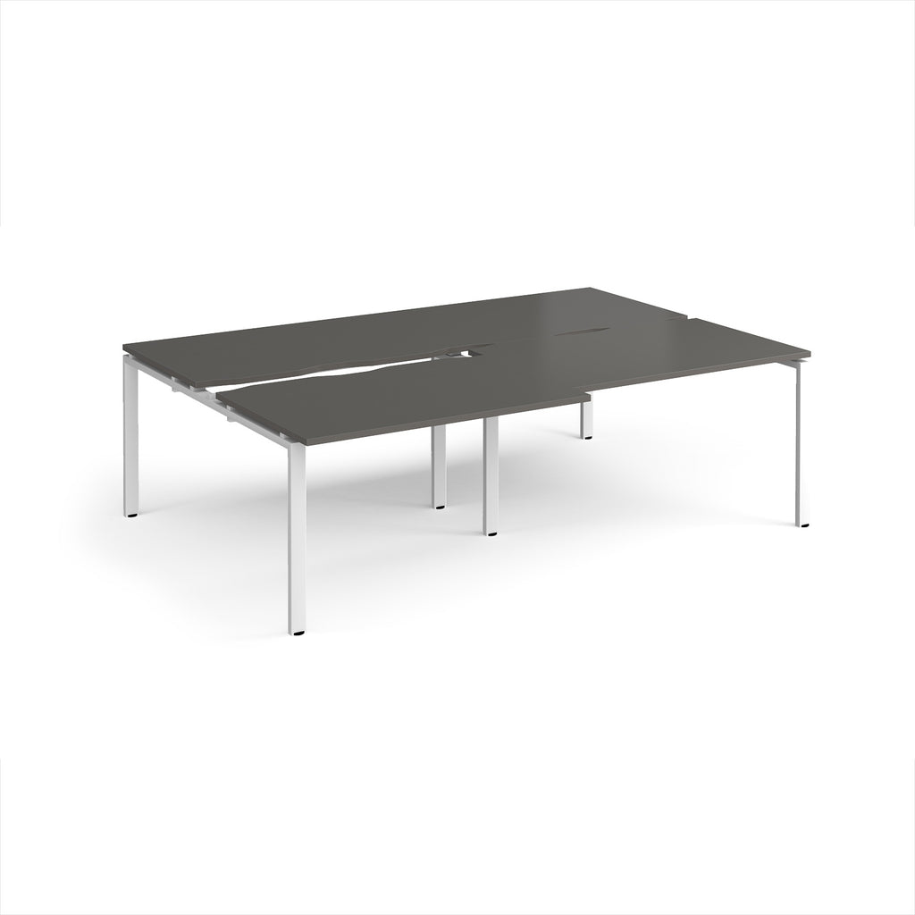 Large modular bench desk with a dark grey worktop, integrated cable access cut-outs, and white metal legs, shown on a white background.