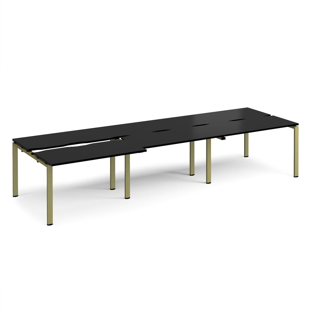 Large modular bench desk with a black worktop, integrated cable access cut-outs, and green metal legs, shown on a white background.