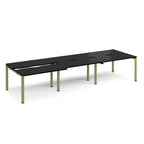 Large modular bench desk with a black worktop, integrated cable access cut-outs, and green metal legs, shown on a white background.