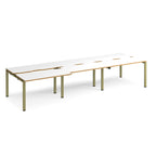Large modular bench desk with white panels and wood-effect edging, integrated cable access cut-outs, and green metal legs, shown on a white background.
