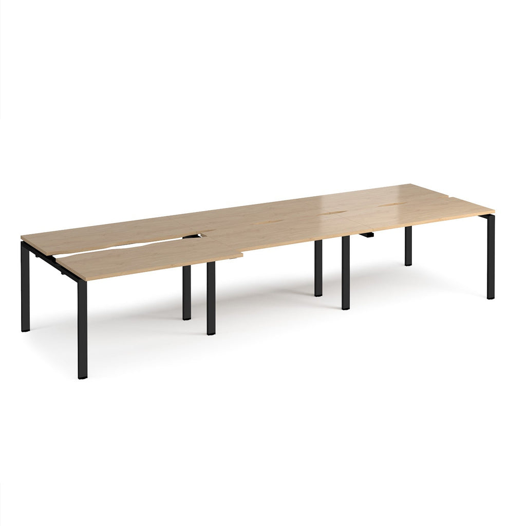 Large modular bench desk with a light wood-effect top, integrated cable access cut-outs, and black metal legs, shown on a white background.