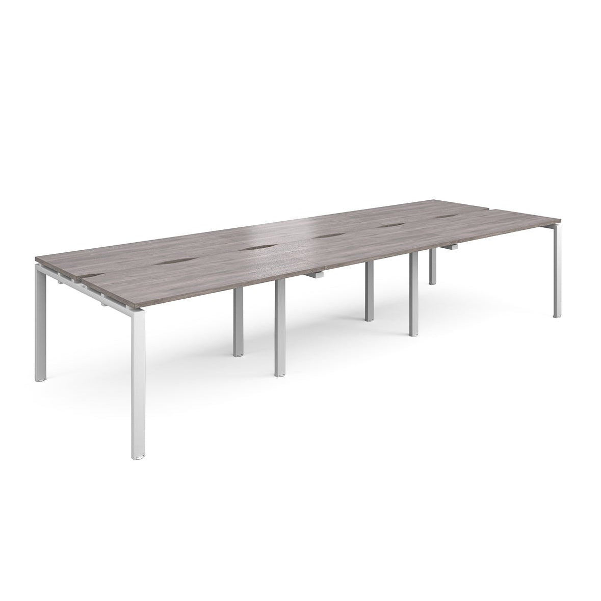 Large modular bench desk with a grey wood-effect top, integrated cable access slots, and white metal legs, shown on a white background.
