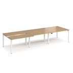 Large modular bench desk with a light wood-effect top, integrated cable access cut-outs, and silver metal legs, shown on a white background.