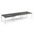 Large modular bench desk with a dark grey worktop, integrated cable access cut-outs, and silver metal legs, shown on a white background.
