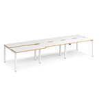 Large modular bench desk with white panels and wood-effect edging, integrated cable access cut-outs, and silver metal legs, shown on a white background.