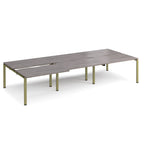 Large modular bench desk with a grey wood-effect top, integrated cable access slots, and green metal legs, shown on a white background.