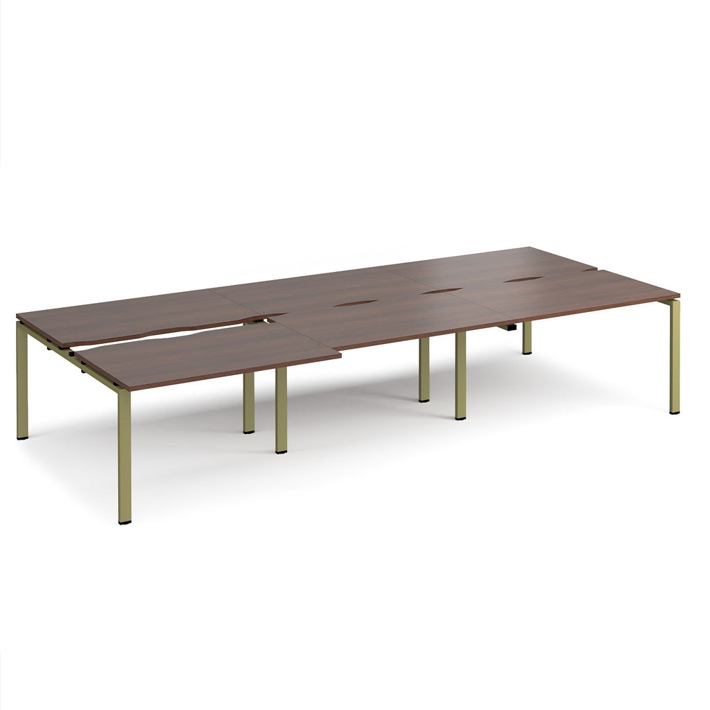 Large modular bench desk with a dark wood-effect top, integrated cable access cut-outs, and green metal legs, shown on a white background.