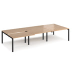 Large modular bench desk with a light wood-effect top, integrated cable access cut-outs, and black metal legs, shown on a white background.