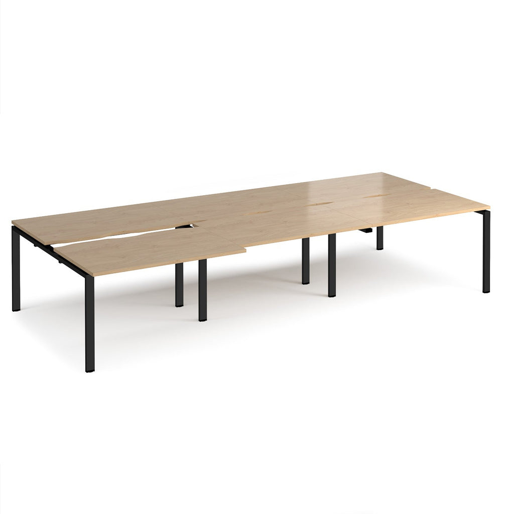 Large modular bench desk with a light oak wood-effect top, integrated cable access cut-outs, and black metal legs, shown on a white background.