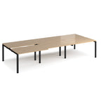 Large modular bench desk with a light oak wood-effect top, integrated cable access cut-outs, and black metal legs, shown on a white background.