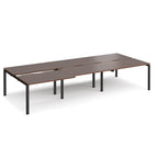 Large modular bench desk with a dark wood-effect top, integrated cable access cut-outs, and black metal legs, shown on a white background.