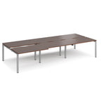 Large modular bench desk with a dark wood-effect top, integrated cable access cut-outs, and silver metal legs, shown on a white background.