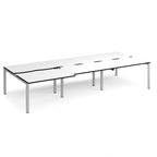 Large modular bench desk with a white worktop, contrasting black edge detail, integrated cable access cut-outs, and silver metal legs, shown on a white background.
