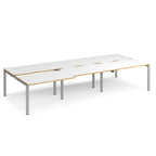 Large modular bench desk with white panels and wood-effect edging, integrated cable access cut-outs, and silver metal legs, shown on a white background.