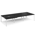 Large modular bench desk with a black worktop, integrated cable access cut-outs, and white metal legs, shown on a white background.