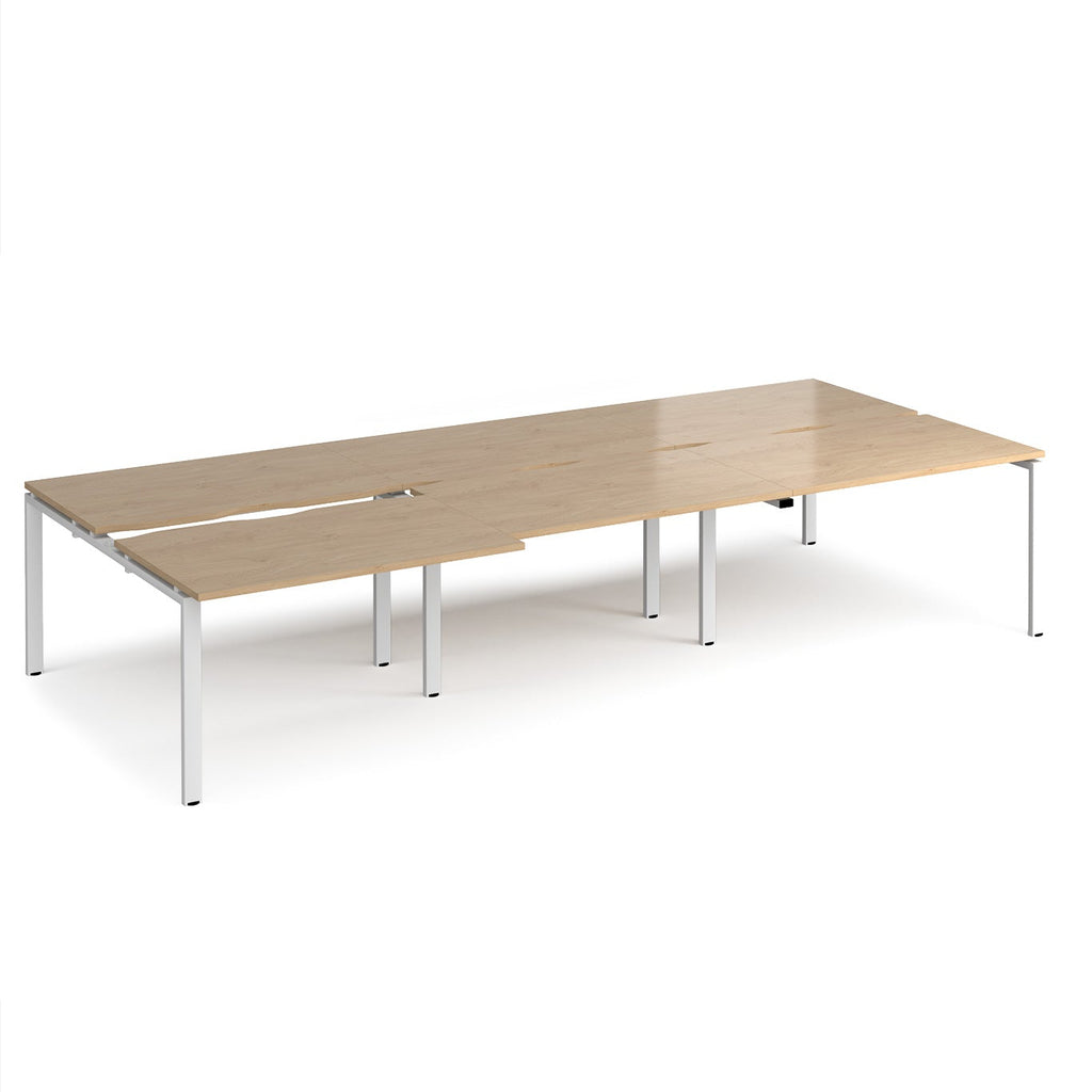 Large modular bench desk with a light oak wood-effect top, integrated cable access cut-outs, and white metal legs, shown on a white background.