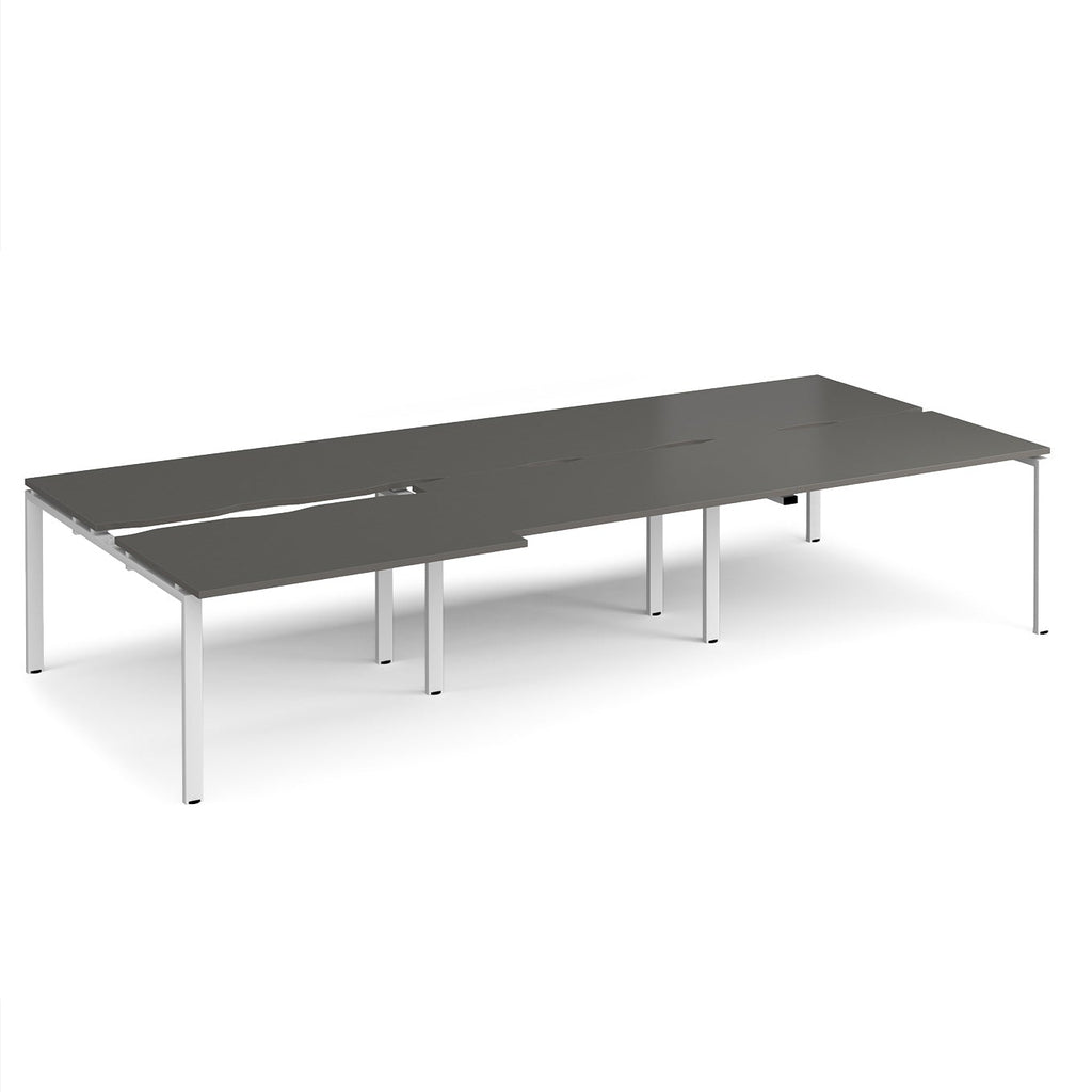 Large modular bench desk with a dark grey worktop, integrated cable access cut-outs, and white metal legs, shown on a white background.