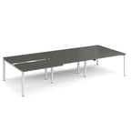 Large modular bench desk with a dark grey worktop, integrated cable access cut-outs, and white metal legs, shown on a white background.