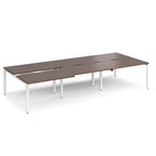 Large modular bench desk with a dark wood-effect top, integrated cable access cut-outs, and white metal legs, shown on a white background.