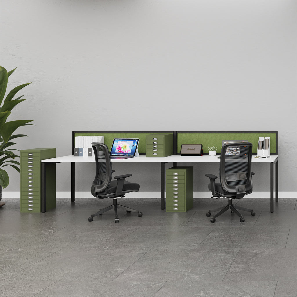 A modern two-person office desk setup with a white desk surface, olive green privacy dividers and storage cabinets, and two black mesh office chairs in a bright, minimalist office space.