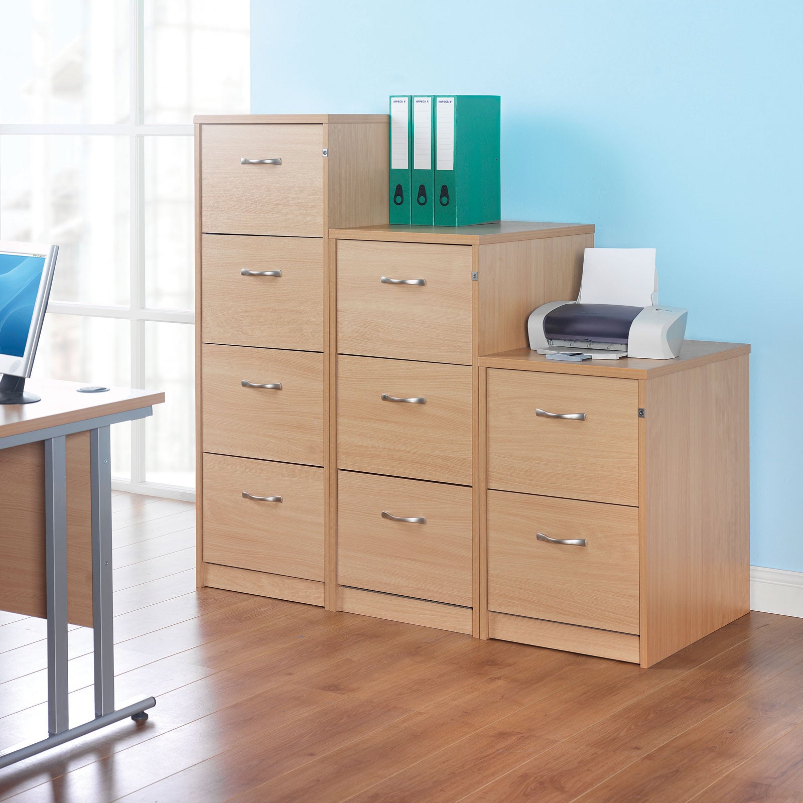 Wooden office furniture set with a printer and binders on a light blue wall background.