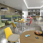 A modern café interior with multiple dining tables and colourful chairs in yellow, red, blue, grey, and green, set against a brick wall and bar area in the background.