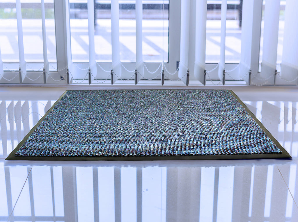 Textured doormat on a reflective floor with a white door in the background