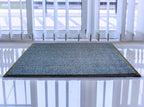 Textured doormat on a reflective floor with a white door in the background