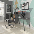 Modern home office setup with a compact desk featuring black hairpin legs, dual monitors on an adjustable arm, an ergonomic office chair, storage cabinet, and geometric patterned accent wall.