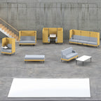 Modern office lounge seating collection with modular yellow and grey sofas, high-back booths, armchairs, and tables arranged in an open-plan space.