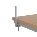 Metal desk clamp with vertical pole attached to the edge of a wooden desk, used for mounting desktop screens securely.