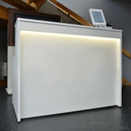 White reception desk with a digital display in an indoor setting