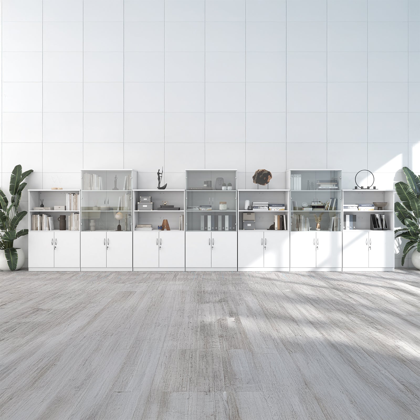 A long modular white storage cabinet and shelving unit set against a white paneled wall, with light wood flooring and potted plants on both sides.