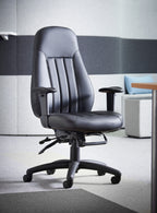 Black leather executive office chair with padded high back, adjustable armrests, and a five-star wheeled base, shown in a modern office environment.