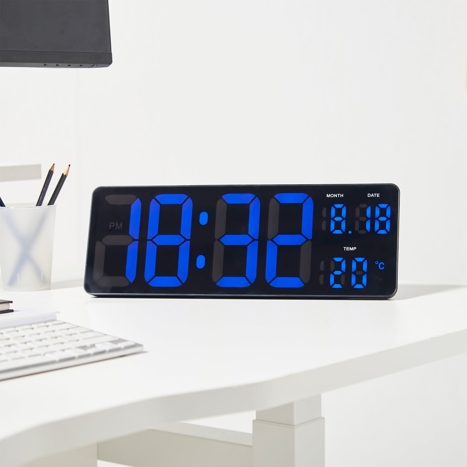 Digital clock with blue LED display on a white desk